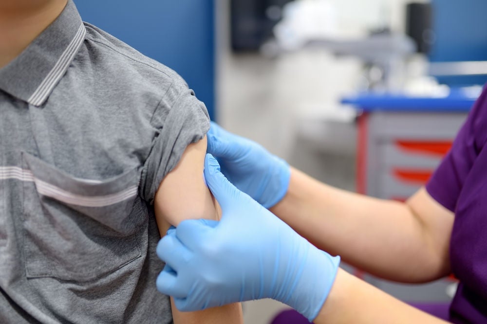a nurse is performing the vaccine inject on a person left arm