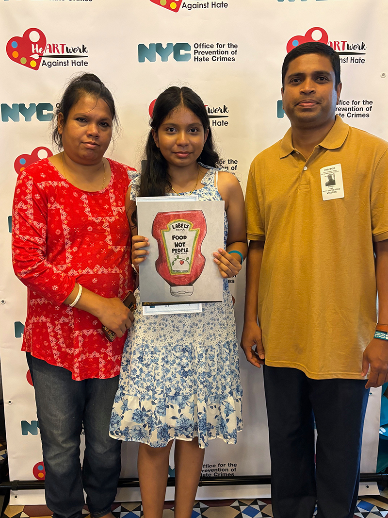 A girl was holding her artwork, standing in between her parents