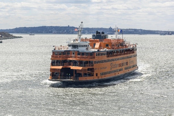 A large orange ferry travels in the New York Harbor.
