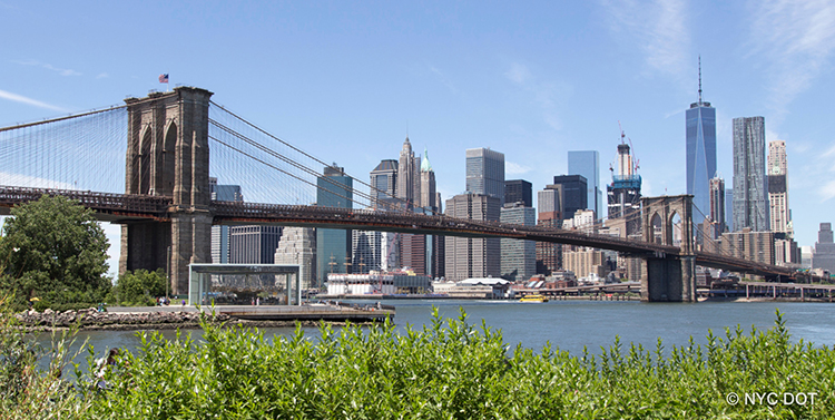 The Brooklyn Bridge expands over the East River with the Lower Manhattan skyline in the background.