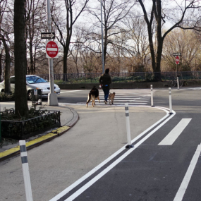 White flexible delineators outline a pedestrian-only space next to the curb.