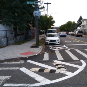 White and black rubber speed bumps on corners near the curb calm right turns.