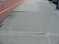 A sidewalk square is sunken in at the corners, creating an improper slope.