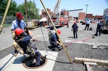 FF James Lopez from Rescue 2 is lowered into a manhole during a confined space demonstration at the Fire Academy. He was assisted by Lt. Sean Parker from the Rescue Battalion, FF Eric Lynch from Squad 1, FF David Giardina from the Rescue Battalion and FF Mike Travers from Rescue 2.