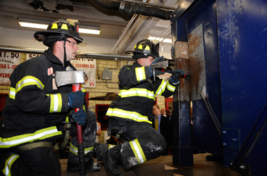 Firefighters Eric Akerberg (left) and Joe Pansini (right) and of Ladder 127 demonstrate the forcible entry simulator.