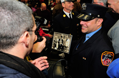 Lt. Shane Mooney holds a photo presented to him by Fire Commissioner Nicholas Scoppetta and Chief of Department Salvatore Cassano. The photo of DAC John Mooney holding his infant son, Shane, was taken on the day DAC Mooney was sworn in as a firefighter in 1978.