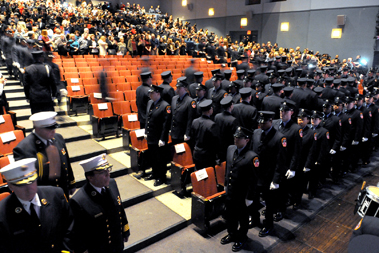 The paramedics and EMTs file into the auditorium for their graduation ceremony.