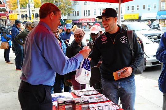 (left to right) a member of FDNY Fire Safety Education helps EMT Bryan Sotomayor sign-up his grandmother for an alarm installation and provides him with educational materials