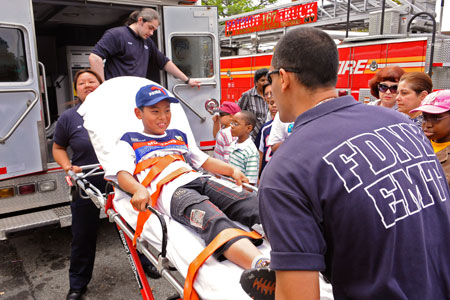 FDNY EMTs show students how they transport a patient in an ambulance.