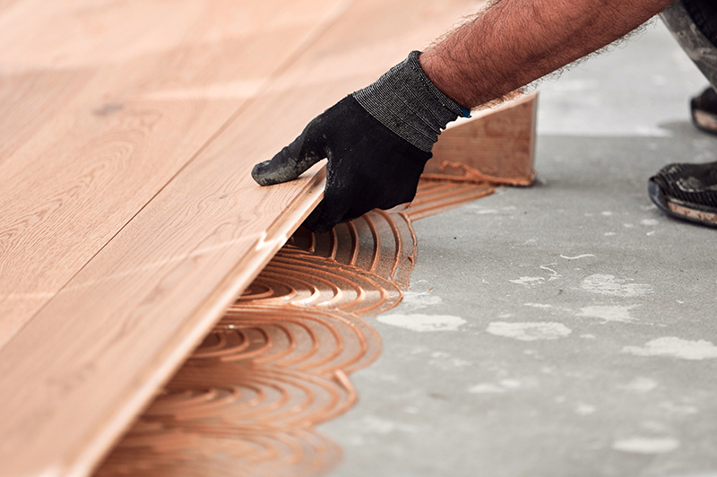 Close-up photo of contractor installing hardwood floors.
                                           