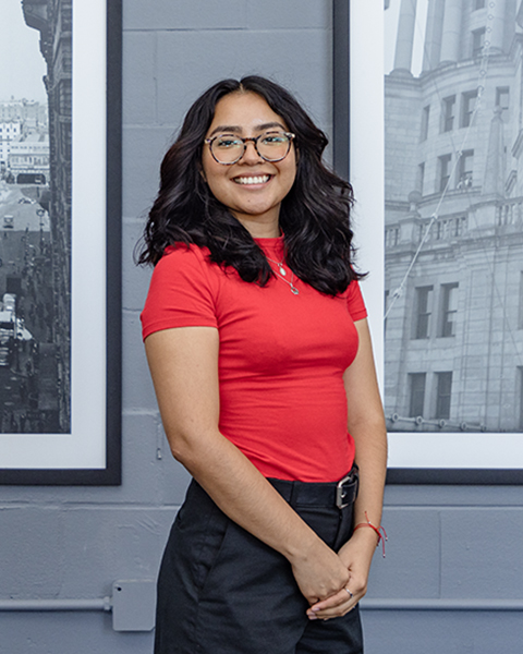 Woman smiling, wearing glasses and a red shirt.