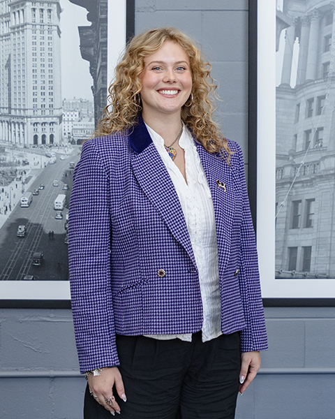 Woman smiling, wearing a blue blazer and white shirt underneath.