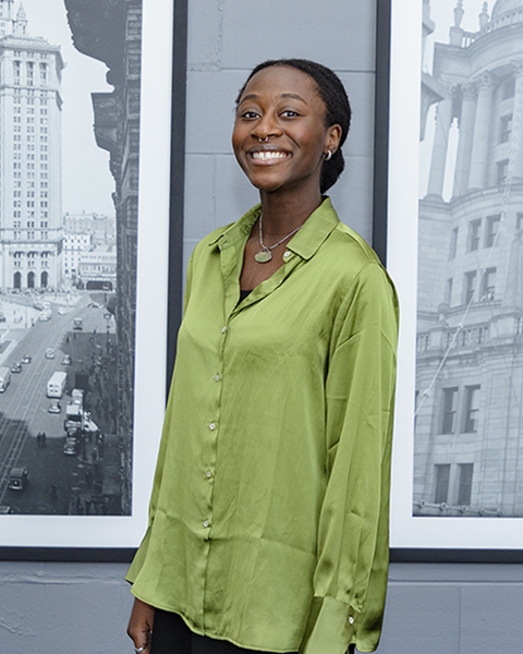 Woman smiling, wearing a green shirt with long sleeves.