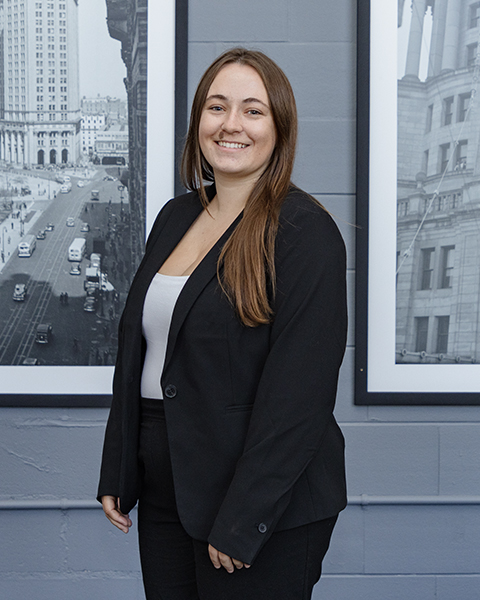 Woman smiling, wearing a black blazer and white shirt.