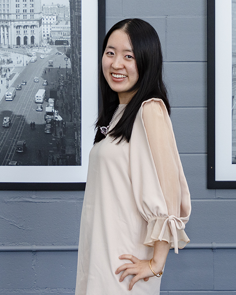 Woman smiling, wearing a crème colored blouse.