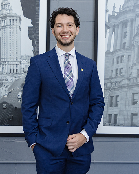 Man smiling, wearing a blue blazer and blue pants.