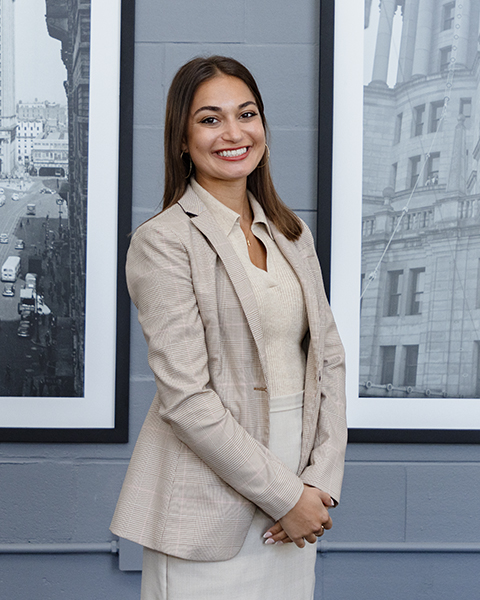 Woman smiling, wearing a tan colored blazer and tan colored shirt.