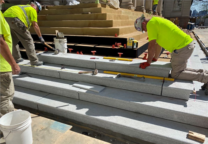 Workers placing the new granite treads and risers at the historic City Hall steps.