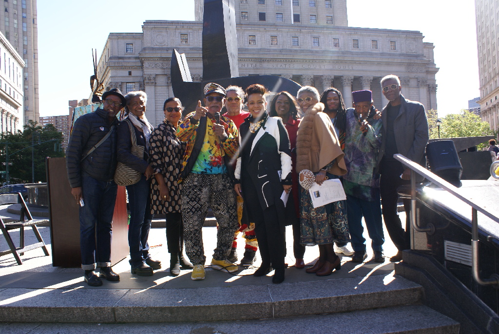 Event partners smile in front of the Triumph of the Human Spirit sculpture. 