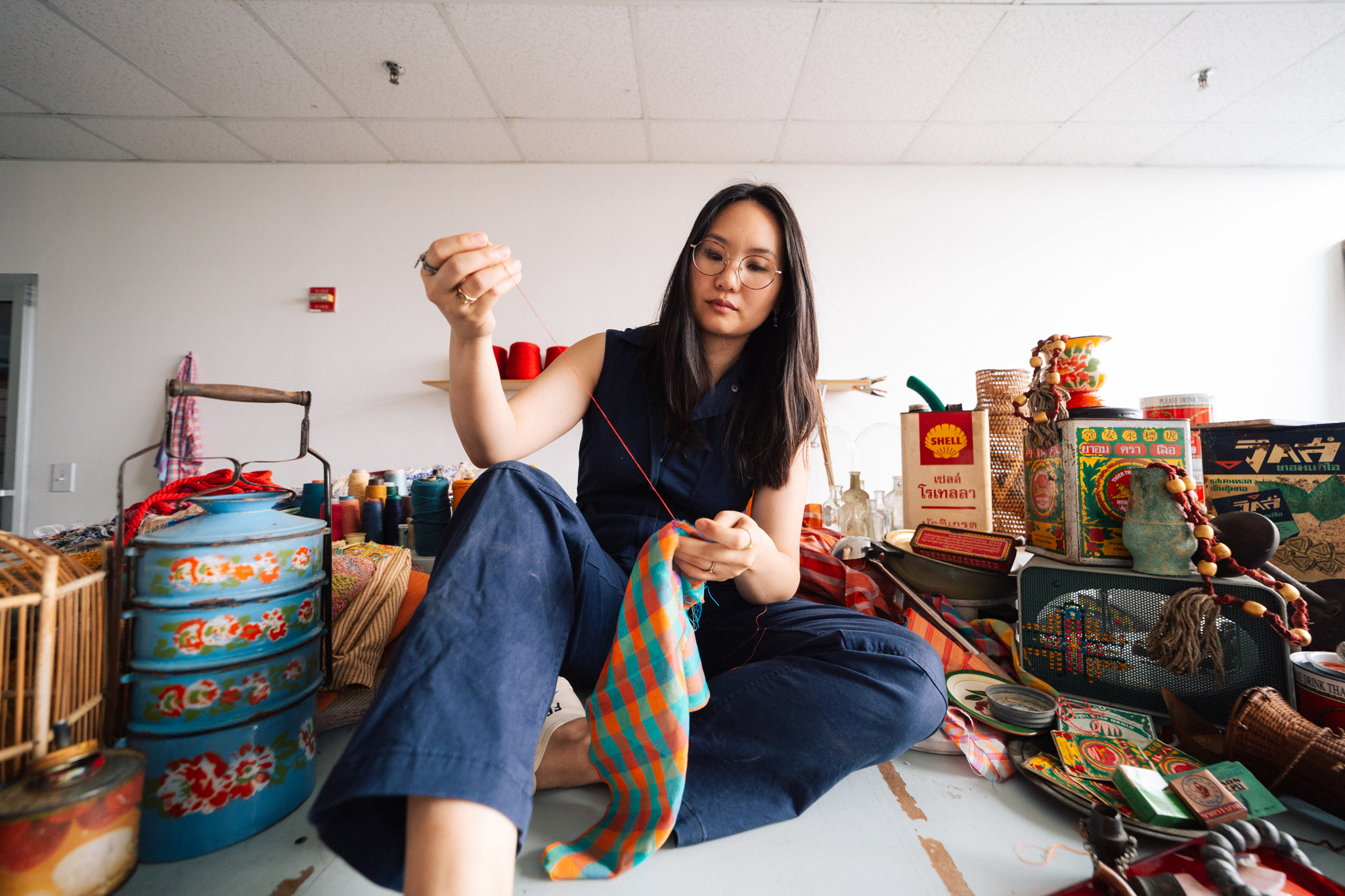 Surrounded by relics from Thailand, Phingbodhipakkiya sews in the MFTA studio.