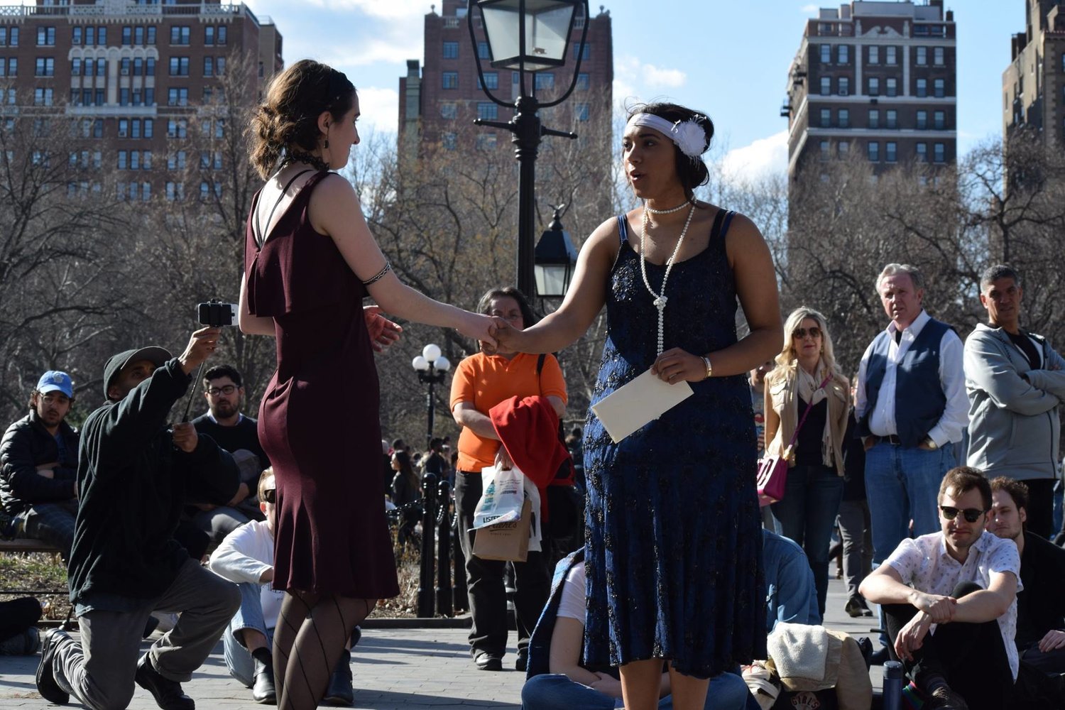 McCain performs with an actor wearing a flapper dress outside in front of a crowd. 