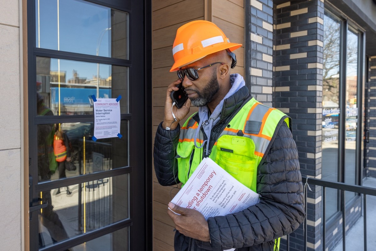 A CCL on site making a phone call holding papers wearing construction helmet