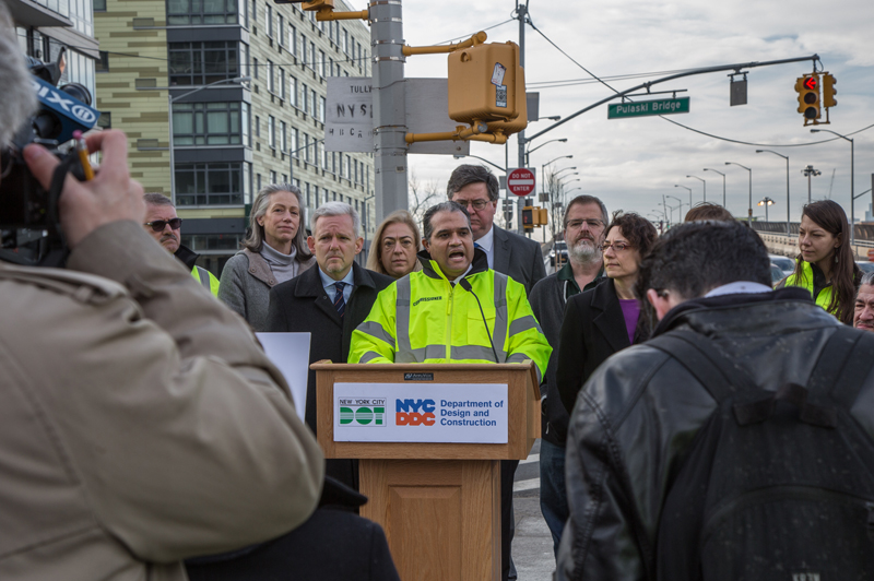 Commissioner Peña-Mora speaks behind a podium at an intersection in LIC.