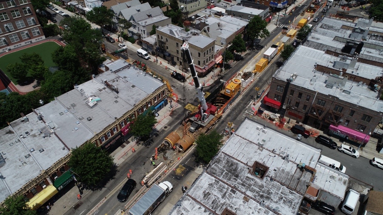 Micro-tunneling techniques eliminated the need for disruptive open trench construction through a residential neighborhood. Here a crane prepares to lower segments of the new 96-inch diameter sewer down a shaft so they can be installed in the new tunnel below the street.