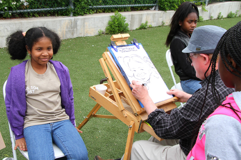 girl sitting in chair while having a caricature made of her