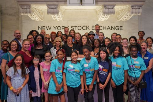 NYC Kids RISE participants, government leaders, and staff stand in front of the "New York Stock Exchange" Sign below The Opening Bell®