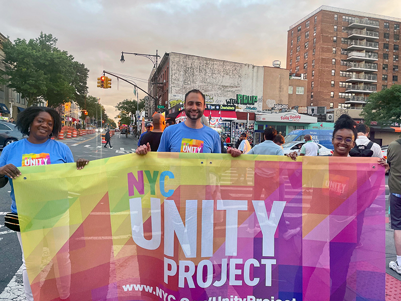 Commissioner Sideya Sherman, the Mayor's Office of Equity, Ronald Porcelli, Senior Policy Advisor for the NYC Unity Project and Dabash Negash, Acting Deputy Exec. Director, the Mayor's Office of Equity, holding the NYC Unity Project banner