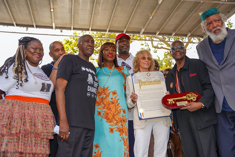 a group of people, a woman at the center holding a proclamation