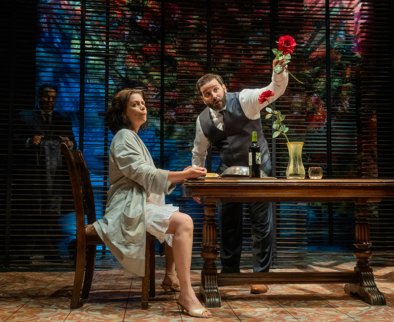 Woman and man sitting at dinning table while performing on stage