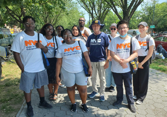 Group of staff and interns all wearing PEU merch pose for the camera outside