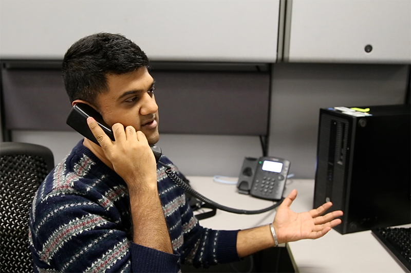 Man sits in desk while speaking on the phone