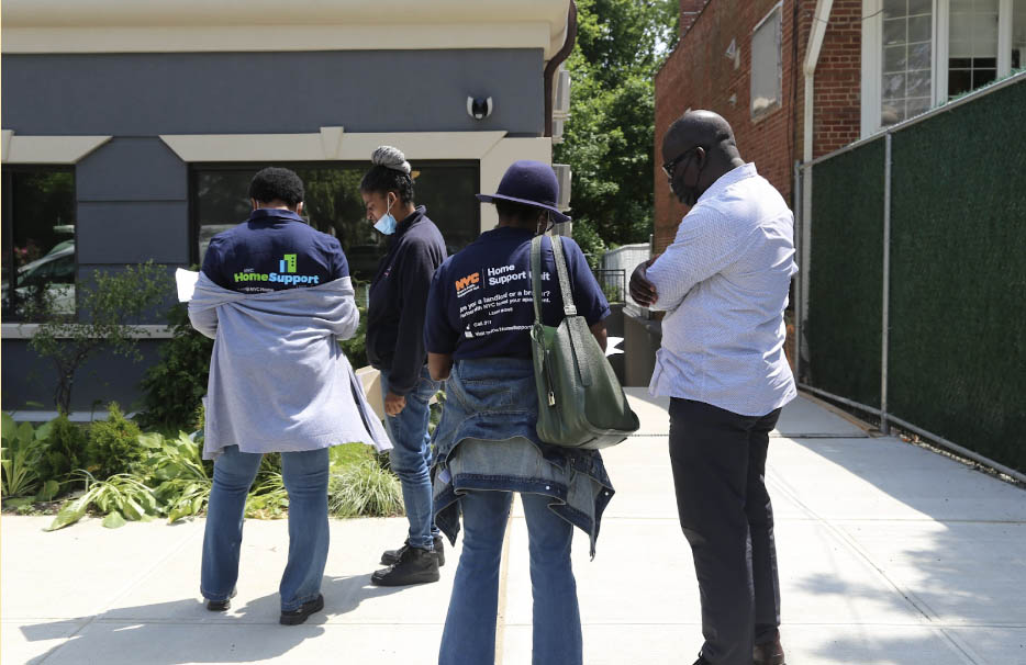 Two PEU staff and two landlords speak to each other, their backs facing the camera. PEU staff wearing Home Support Unit T-shirts