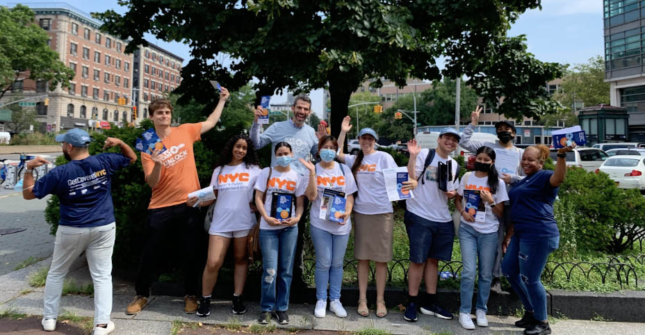 Group of PEU and NYC Care staff holding up flyers about healthcare access and celebrating.