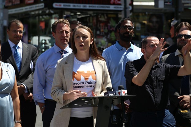 PEU Executive Director, Adrienne Lever, speaks at a microphone during a press conference.