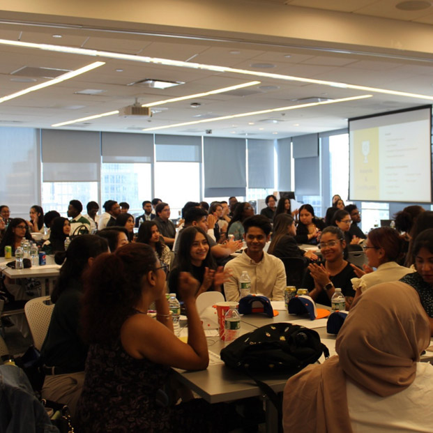 Group of interns gathered in an office talking amongst each other.