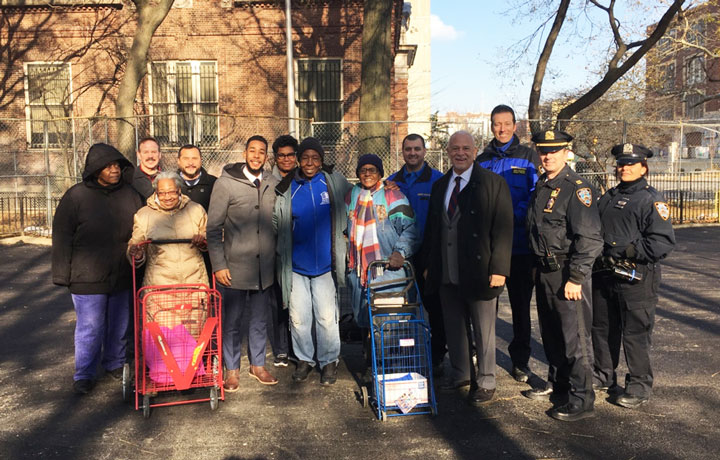 Image of General Manager Michael Kelly and Council Member Antonio Reynoso posing in a group photo with residents of Hylan Houses