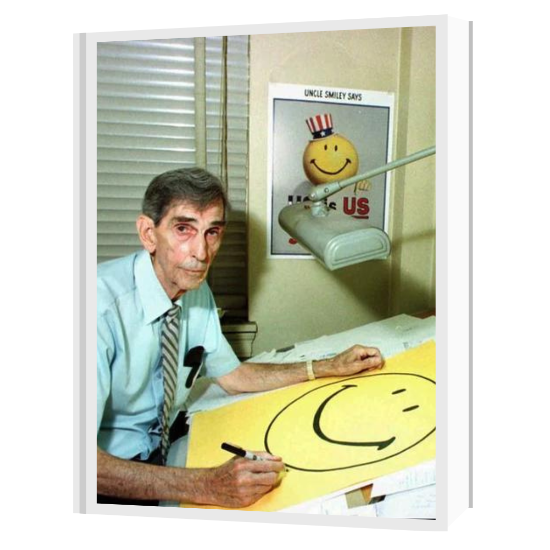 Person with a pen in their hand and a drawing of a smiley face emoji on the desk