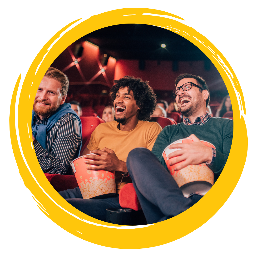 Photo of people smiling and eating popcorn while watching a movie