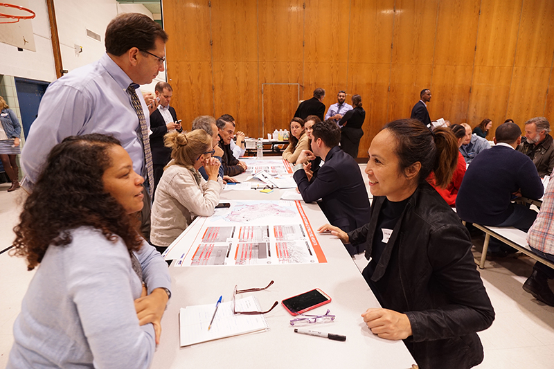 Groups of people sitting at tables with maps of Red Hook and having conversation