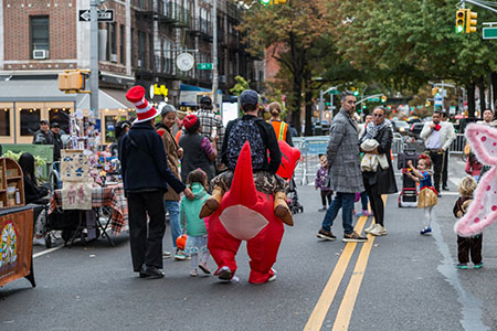 People in Halloween costumes walk down a street in Queens while it is closed to vehicles