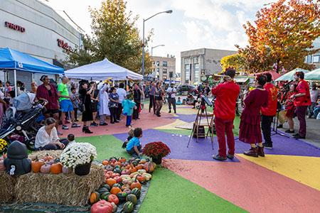 Musicians perform for families on a plaza with a colorful asphalt mural