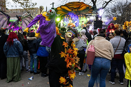 A man dressed in a Halloween costume holds up a scary puppet in front of a stage during a car-free event